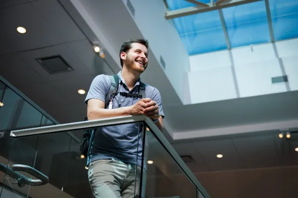 Sinh viên Charlie Brizz mỉm cười rạng rỡ bên lan can cầu thang tại khuôn viên trường