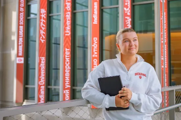 Sinh viên cầm sổ tay đứng trước các bảng chỉ dẫn đa ngôn ngữ tại trung tâm quốc tế